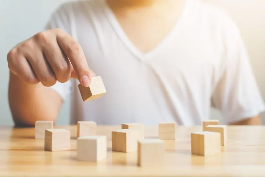 Person thoughtfully arranging wooden cubes